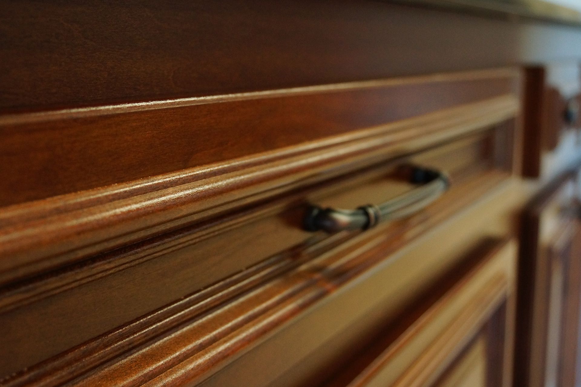 Close-up of a wooden cabinet drawer with a black handle