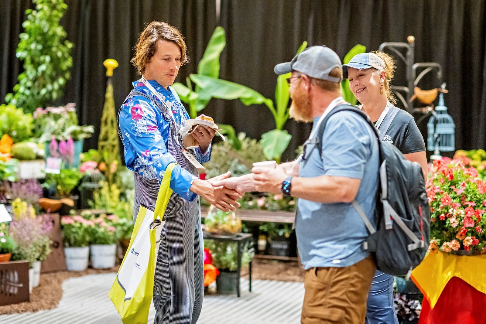 a man is shaking hands with a woman at a flower show .