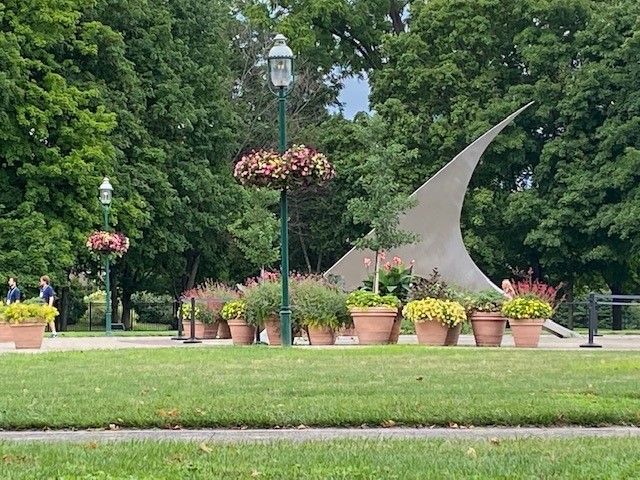 a sculpture in a park with flowers in pots