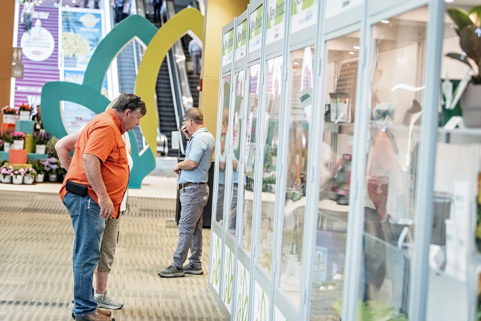 a man in an orange shirt is looking at a display of flowers