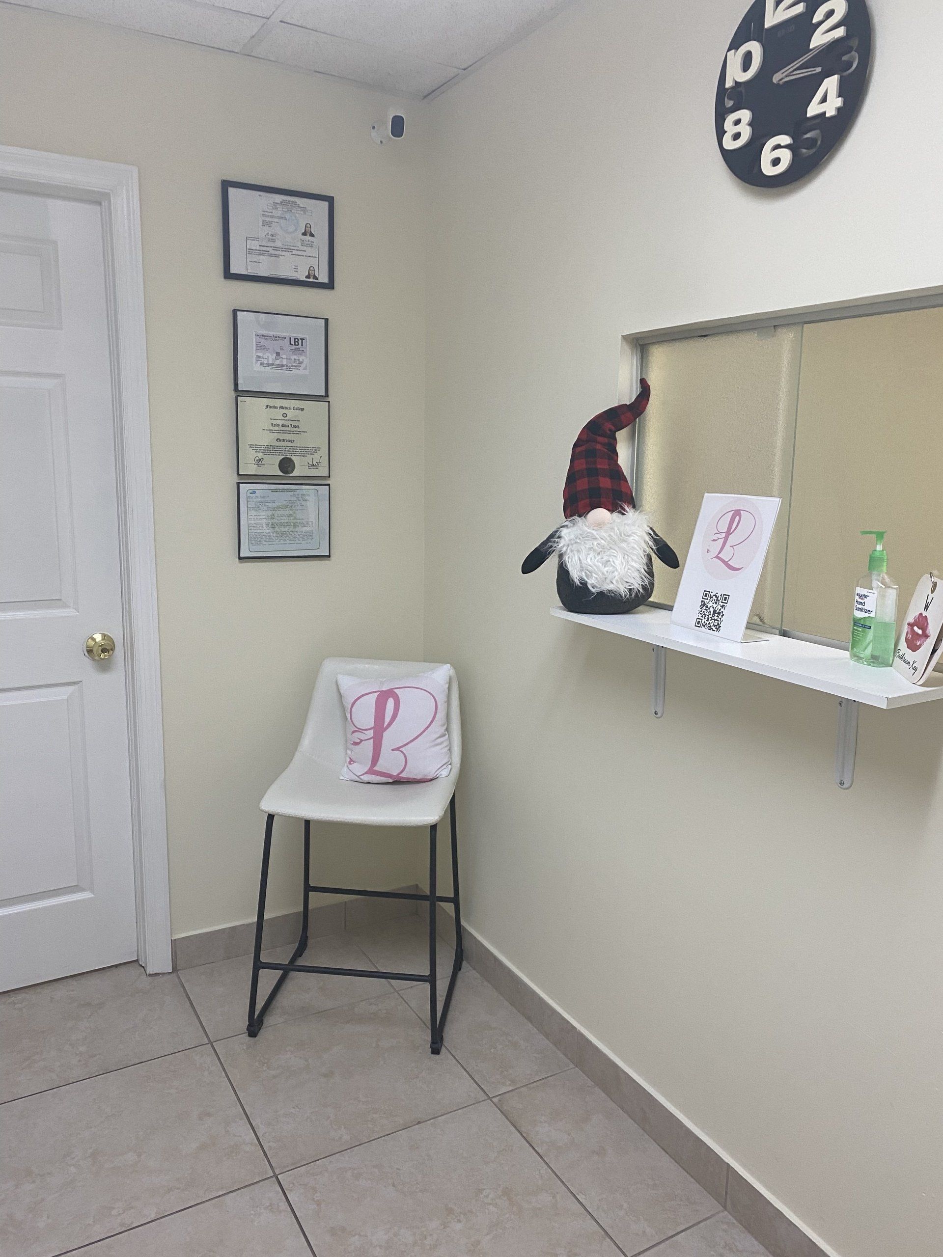 Una pequeña área de recepción de oficina con una silla, arte de pared, reloj y gnomo.