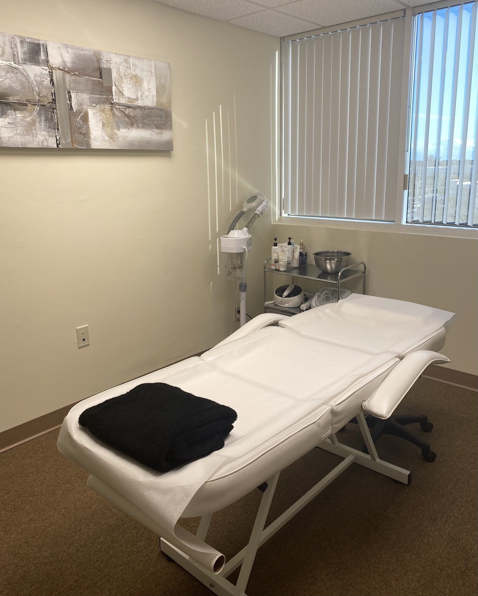 Sala de tratamientos de spa con mesa de masajes, arte y persianas.