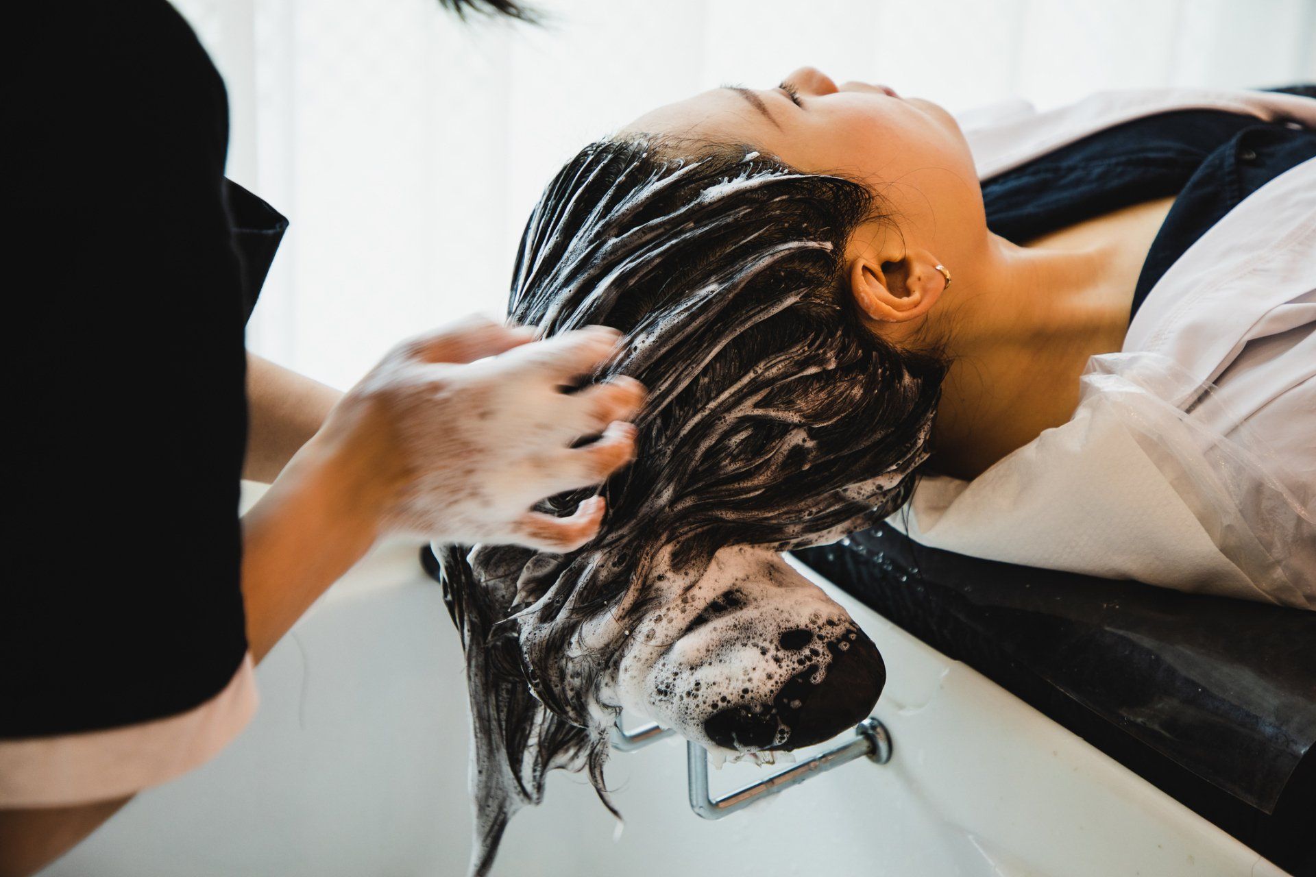 Woman getting her hair washed at a salon, lying back in a sink.