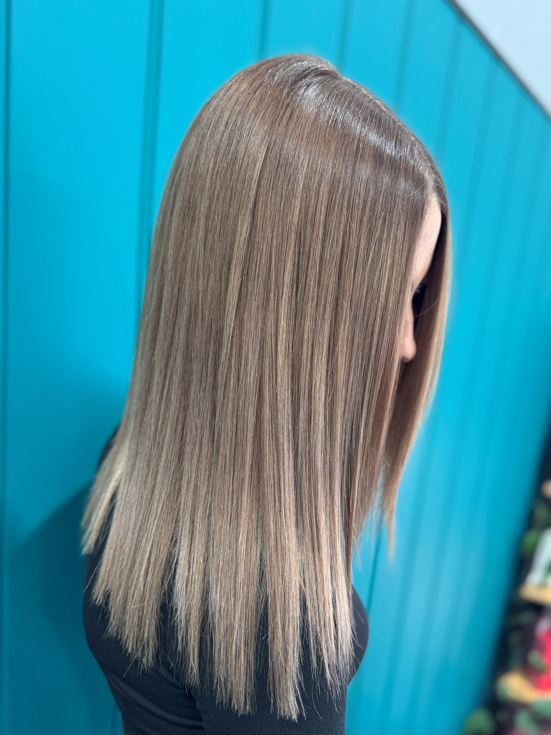 Long straight silver hair with dark roots against a bright blue background