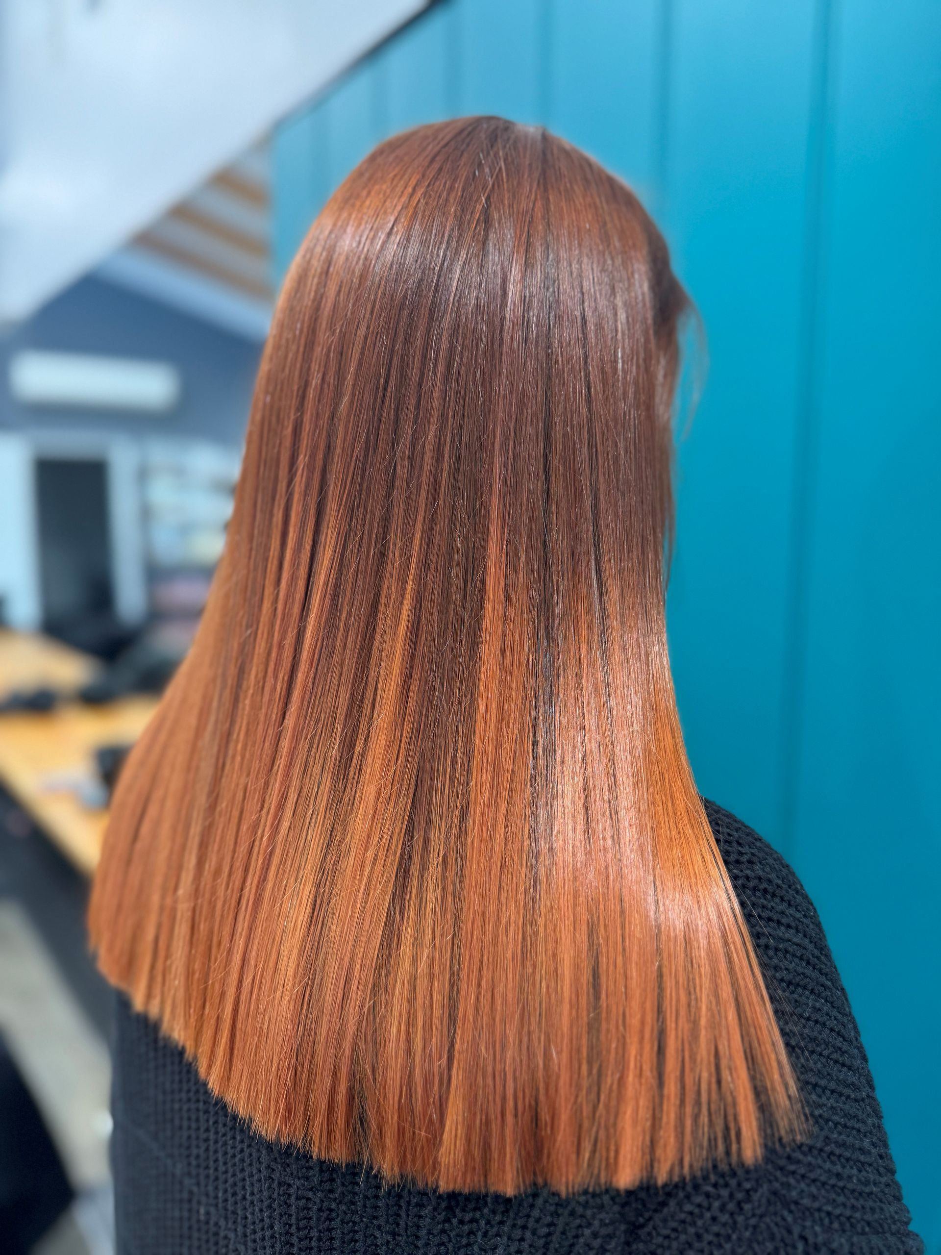 Straight copper-brown hair seen from behind in an indoor setting