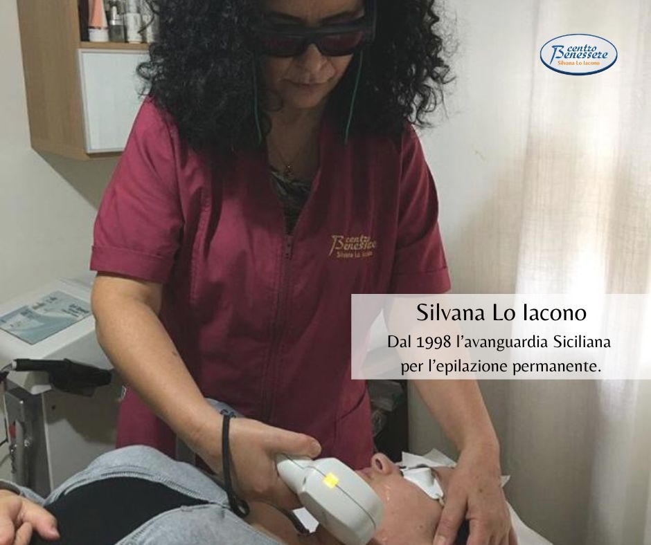 Donna che esegue la depilazione laser sul collo di una cliente. Indossa occhiali protettivi e un'uniforme color bordeaux.