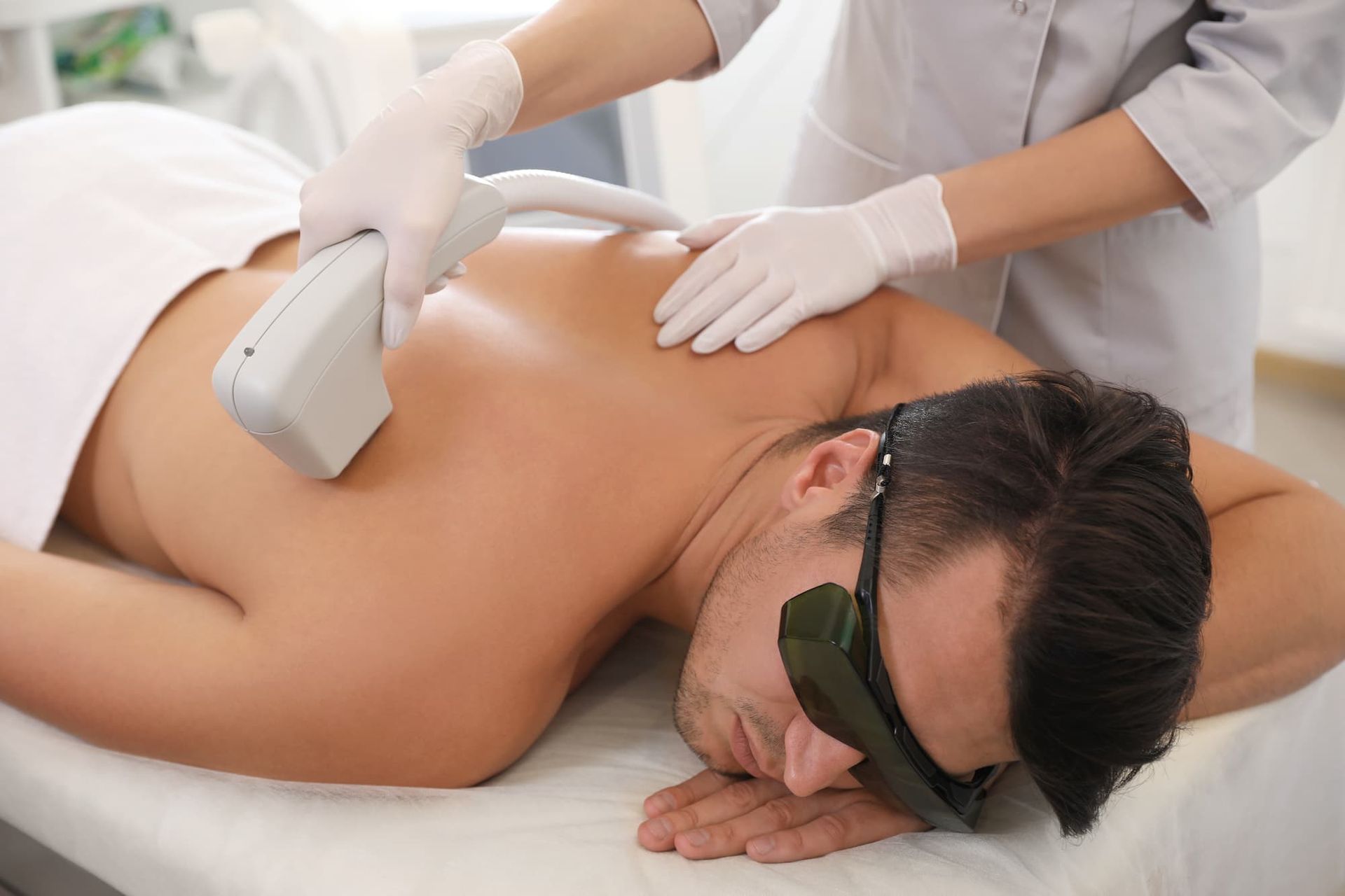 Persona sottoposta a trattamento di epilazione laser sulla schiena, sdraiata su un lettino da massaggio.