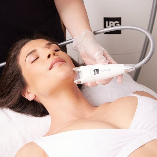 Donna sottoposta a trattamento viso; dispositivo sul collo, tecnico con guanti.