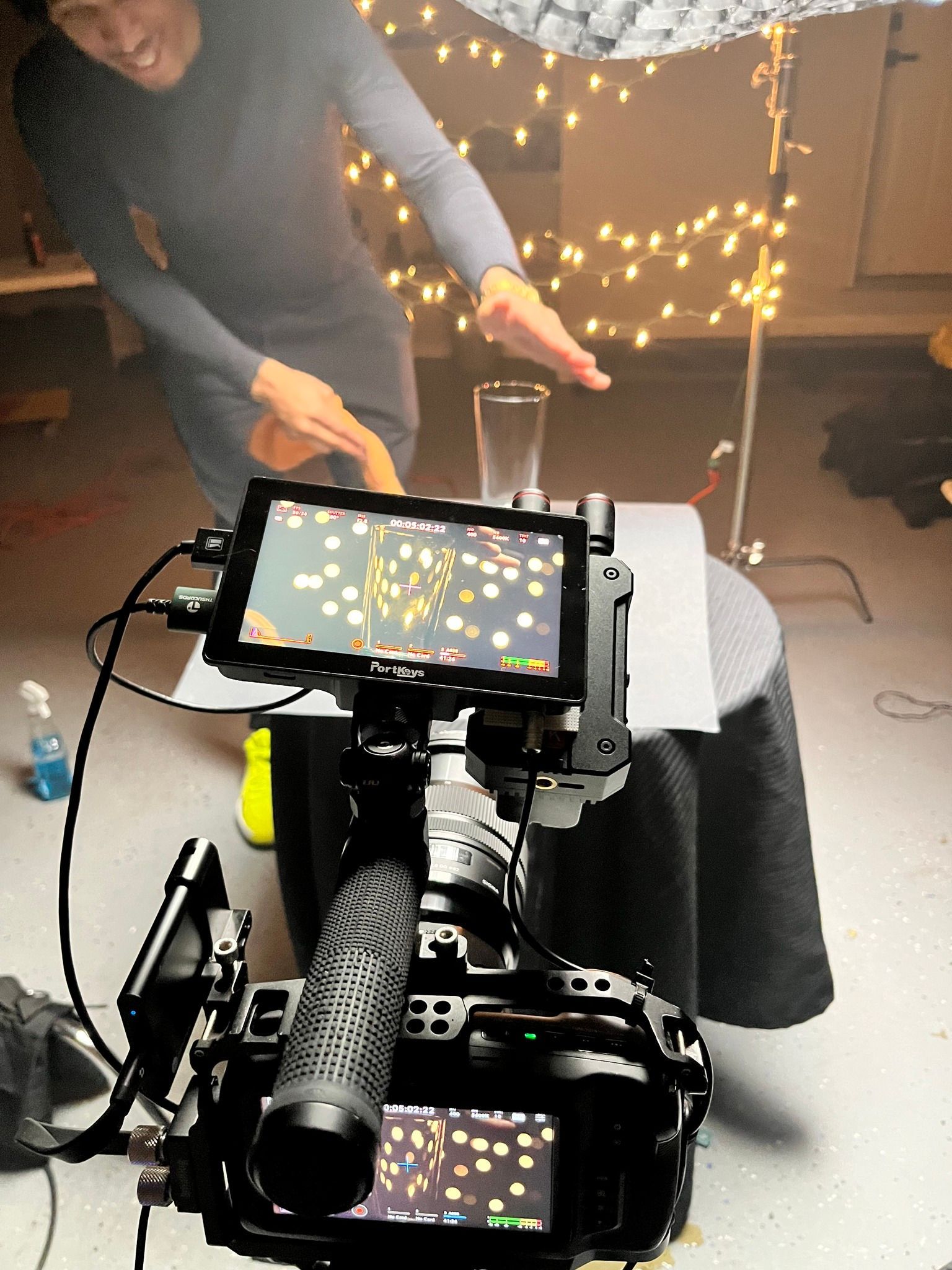 Person leaning over a wheelchair-mounted tablet amid warm string lights indoors