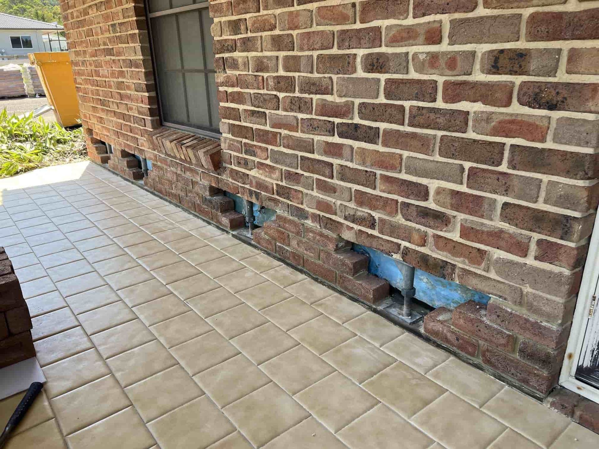 A Brick Wall With A Window And A Tiled Floor — Heritage Bricklaying & Remedial Services In Erina, NSW