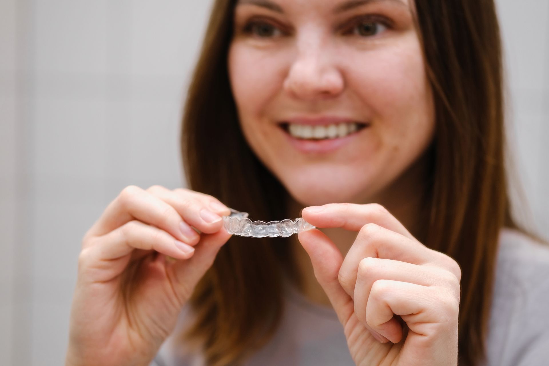 Orthodontics | Woman holding Invisalign clear aligners for straighter teeth in Friendswood TX