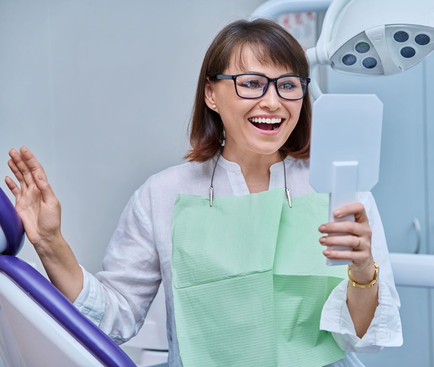 woman smiling looking in mirror at dentist office after getting restorative dental care in Friendswood TX