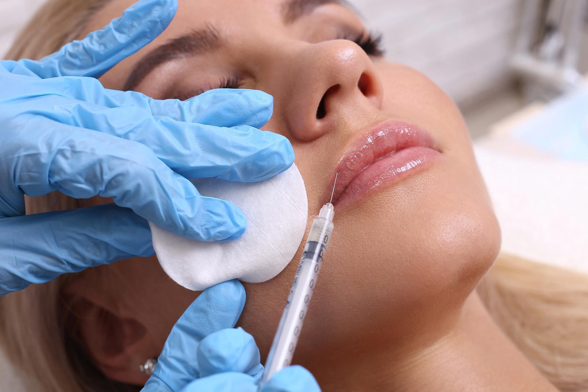 Gloved hands injecting a woman’s cheek with a cosmetic syringe
