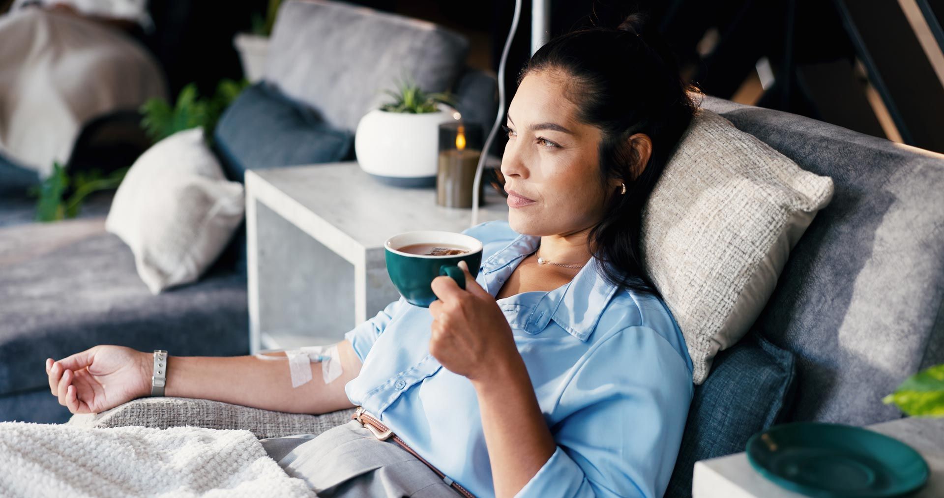 Person relaxing on a couch, holding a cup of coffee in a modern living room.