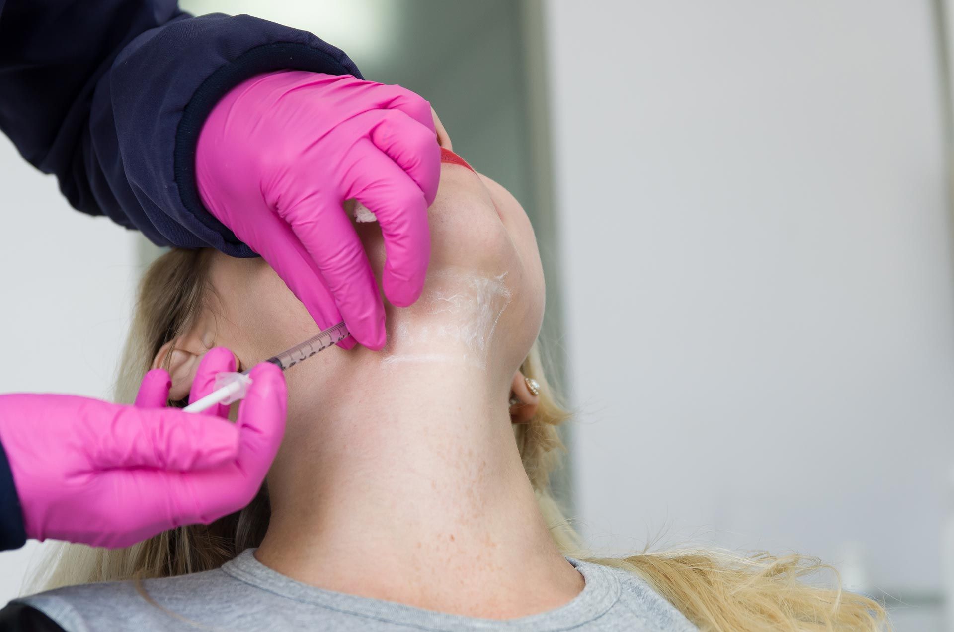 Gloved hands giving an injection in the side of a person’s neck
