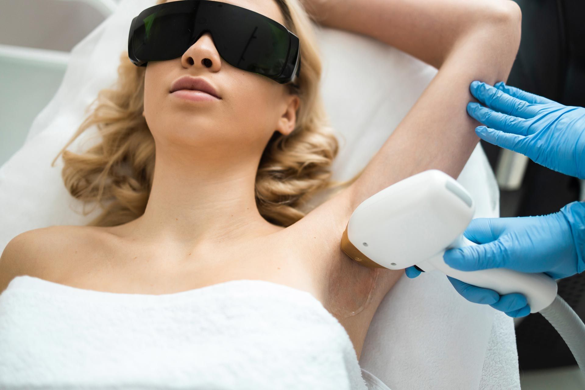 Woman receiving laser hair removal treatment under bright clinic lights