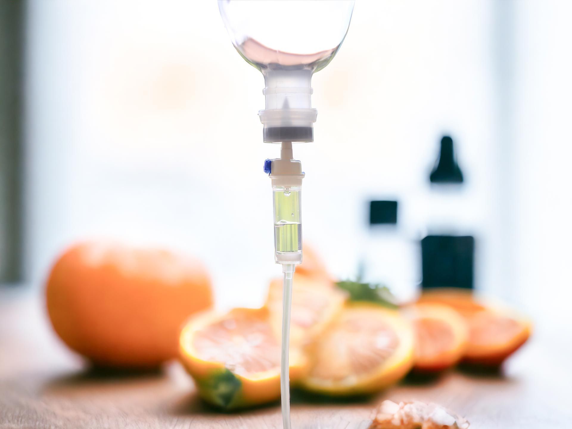 IV drip with sliced citrus fruits on a bright table, suggesting vitamin C infusion
