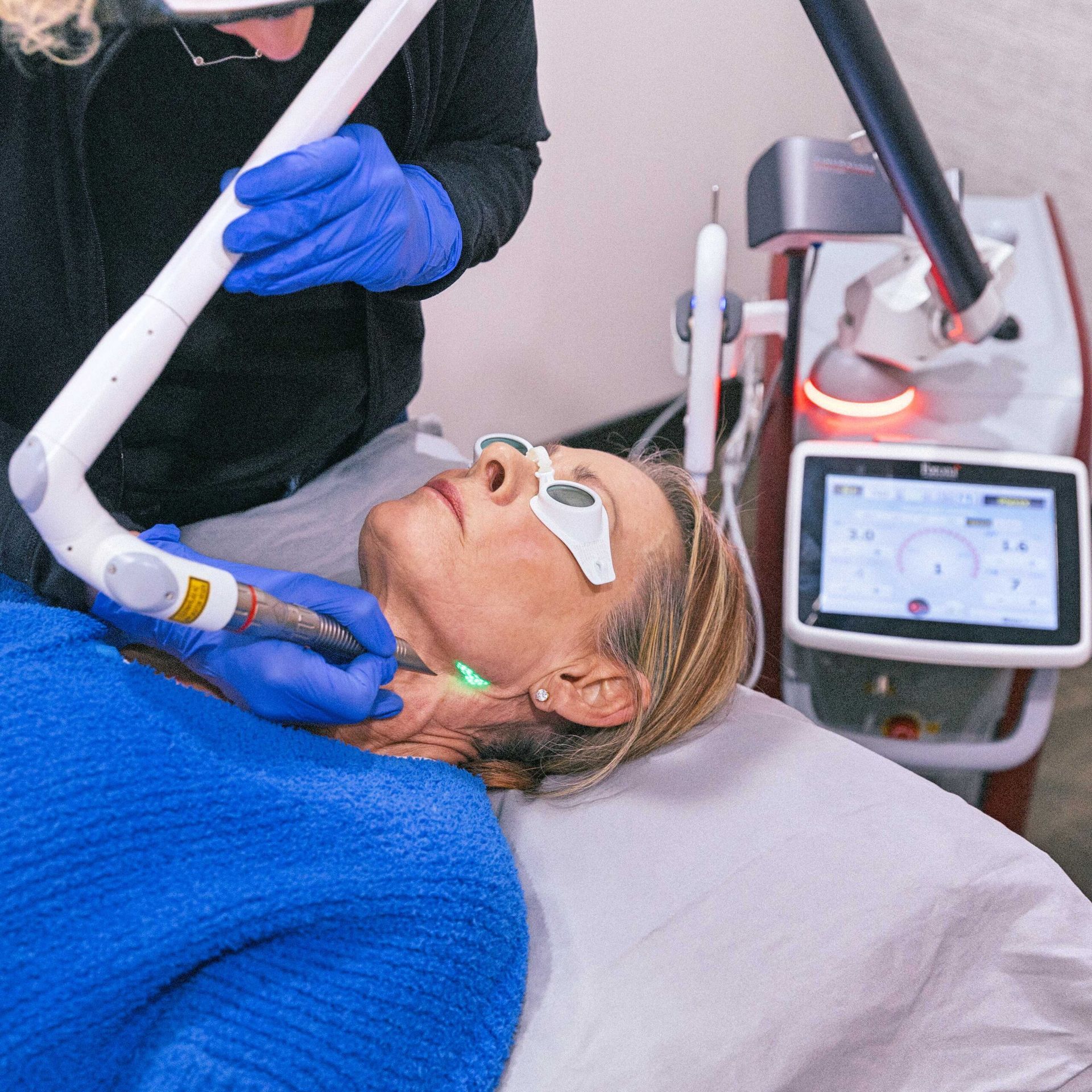 Close-up of a facial treatment on a reclining woman using a handheld beauty device