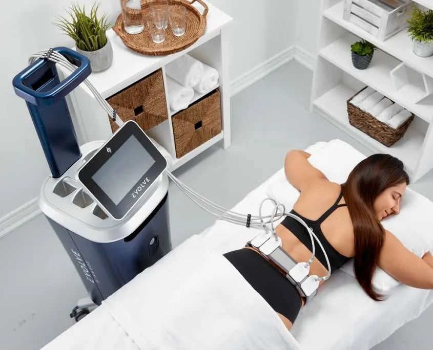 Woman receiving a back treatment on a massage bed beside a blue spa machine