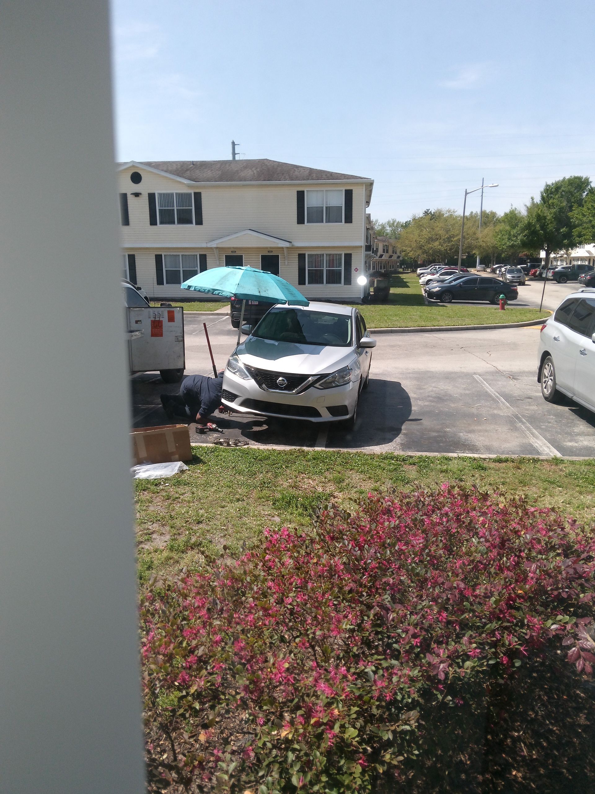 A white car is parked in a parking lot next to a building.