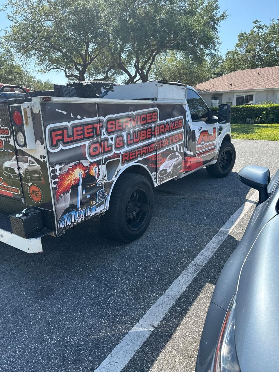 A fleet service truck is parked in a parking lot next to a car.