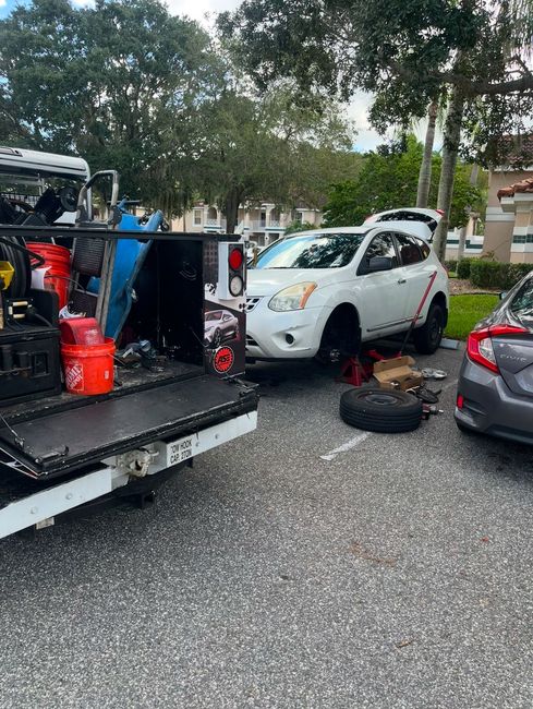 A tow truck is towing a white suv in a parking lot.