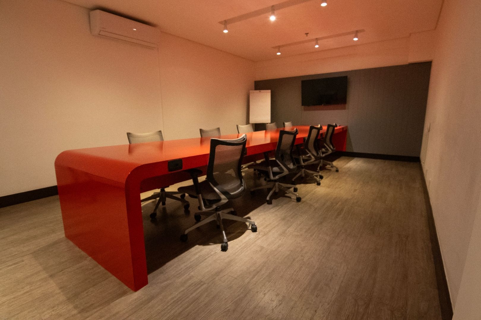 Uma sala de conferências com uma longa mesa e cadeiras laranja.