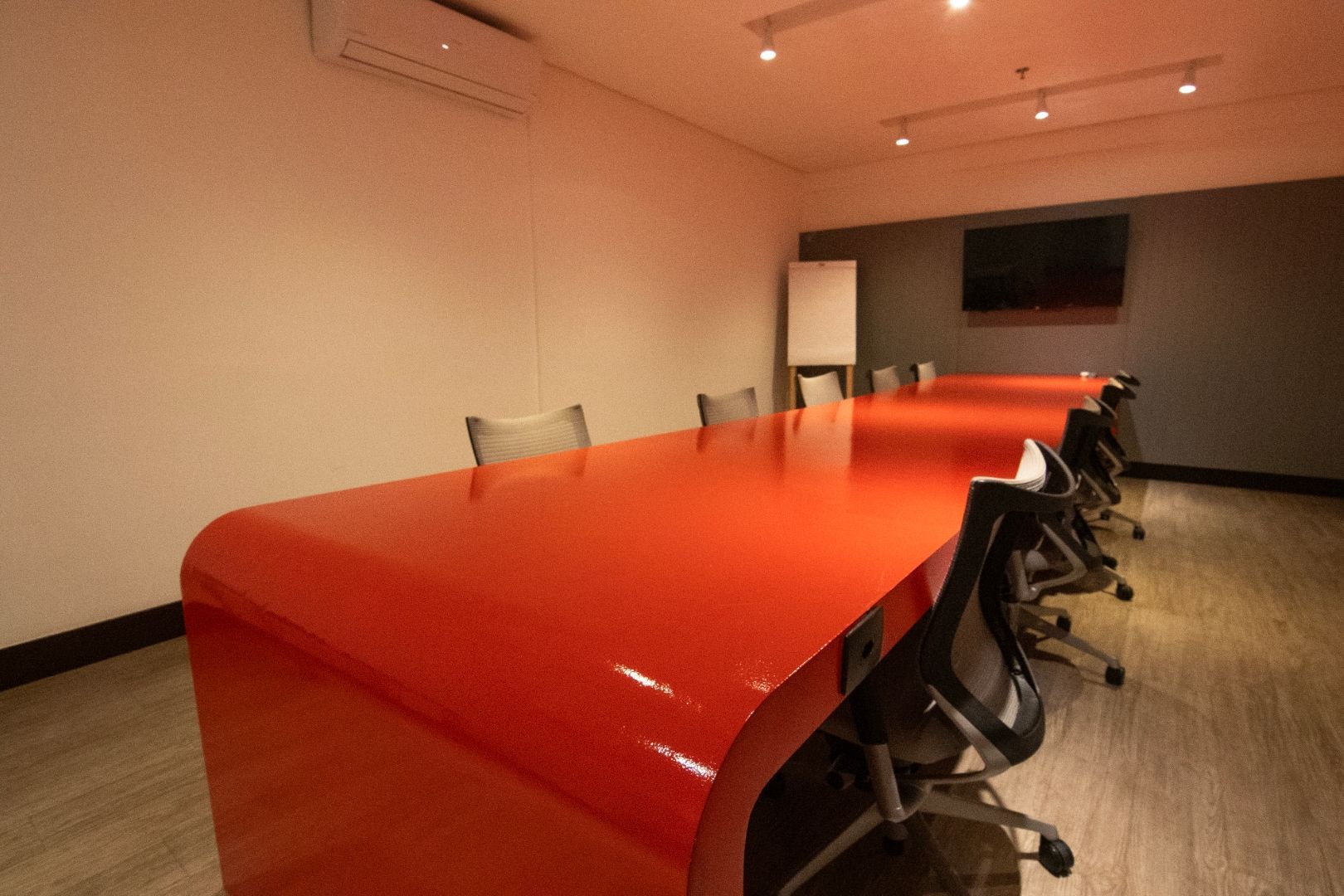 Uma sala de conferências com uma longa mesa vermelha e cadeiras
