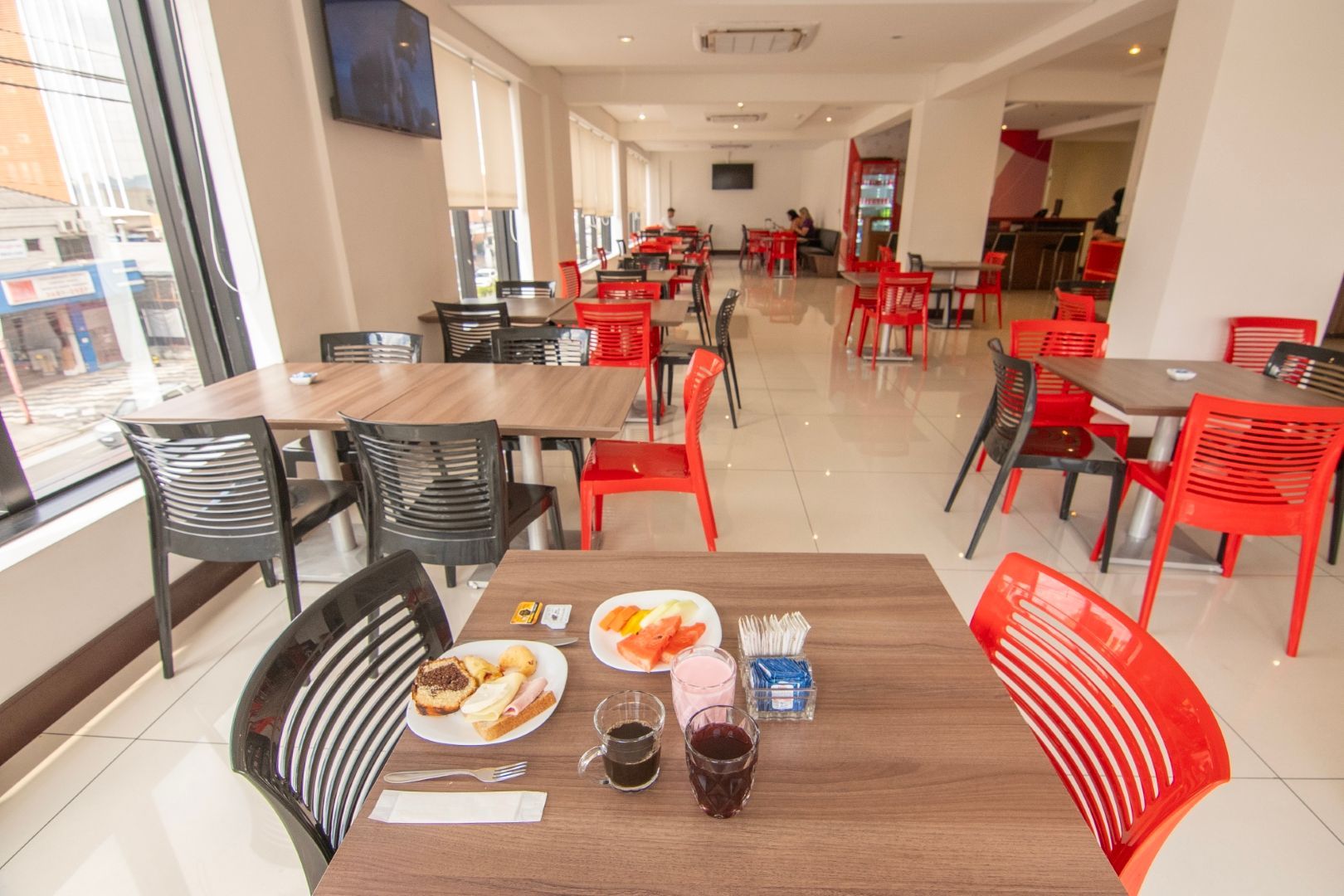 Um restaurante com mesas, cadeiras e pratos de comida.