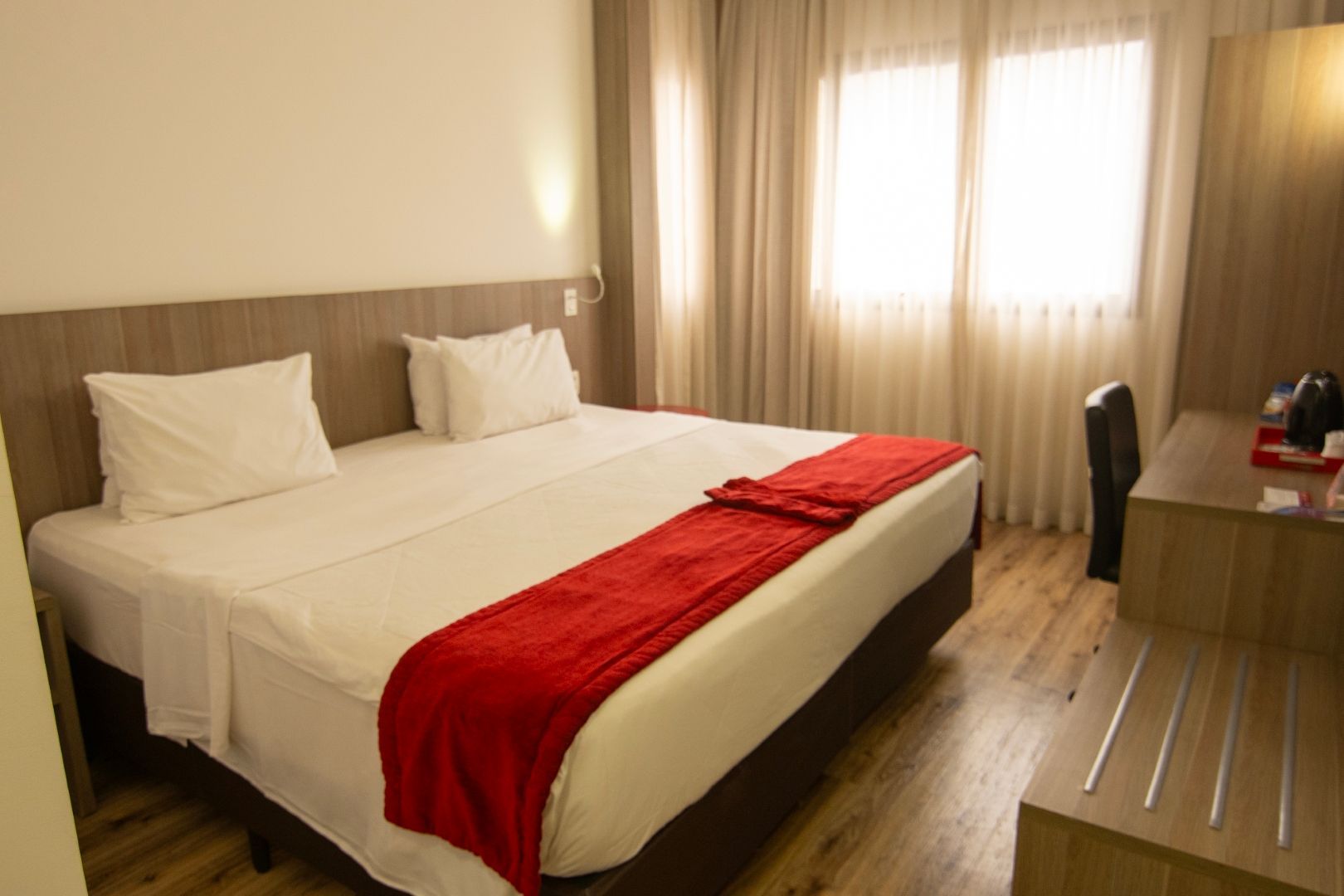 Um quarto de hotel com uma cama king size e um cobertor vermelho