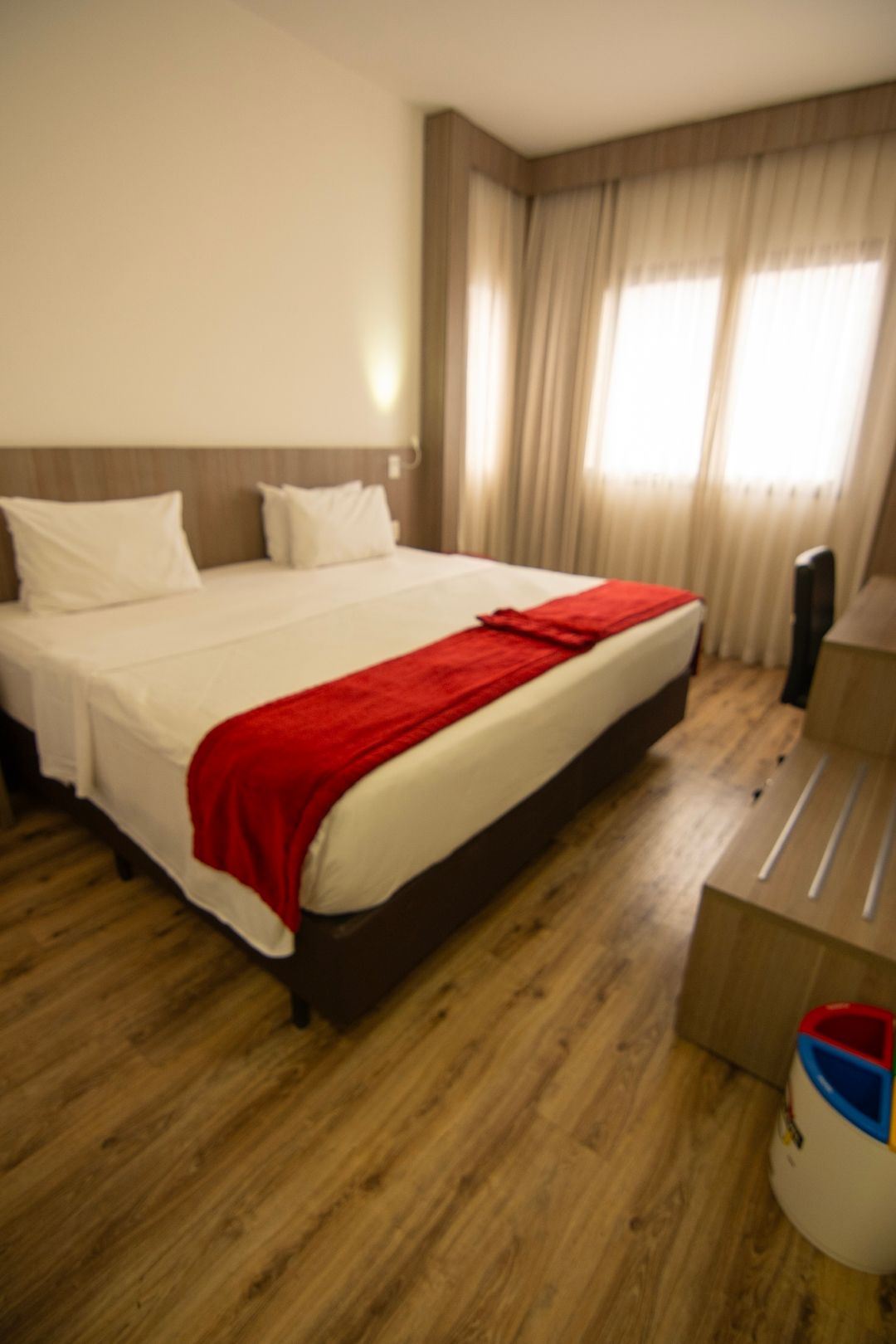 Um quarto de hotel com uma cama grande e um cobertor vermelho