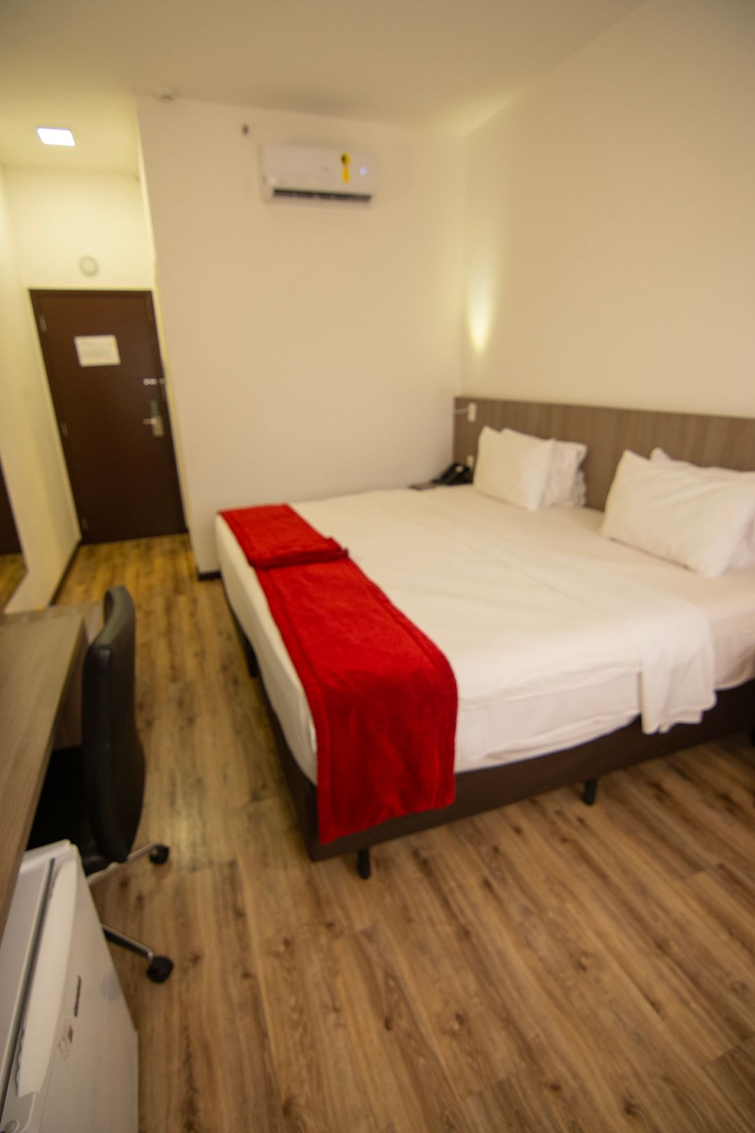 Um quarto de hotel com uma cama grande e um cobertor vermelho