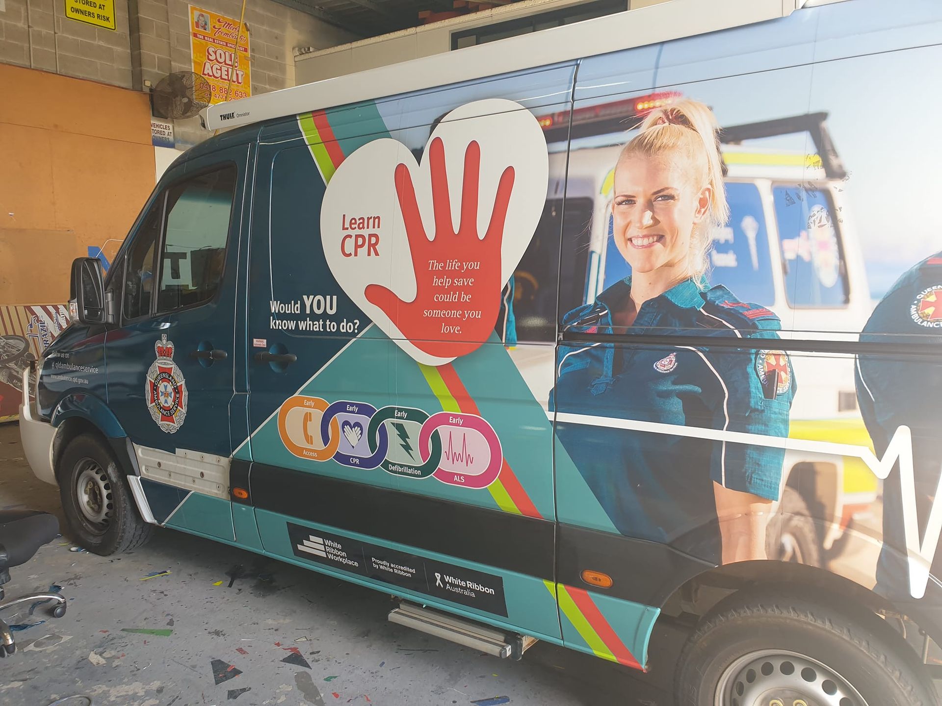 Ambulance van with CPR education graphics, a nurse, and a heart-shaped hand symbol.