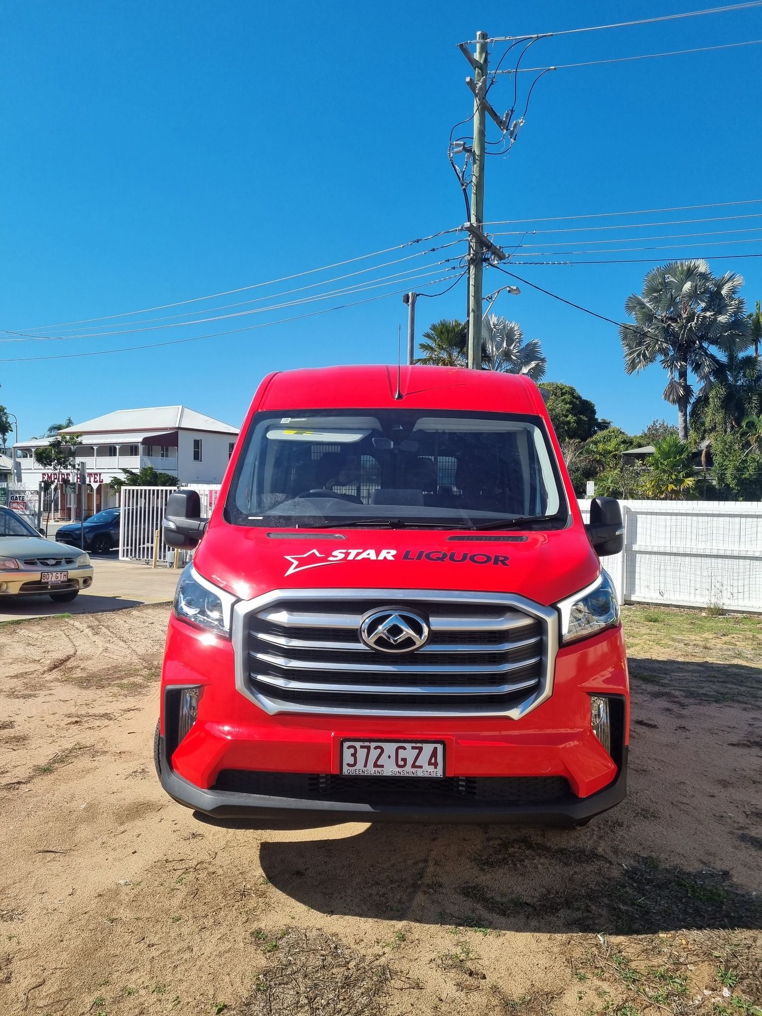 Red van parked on dirt, with 
