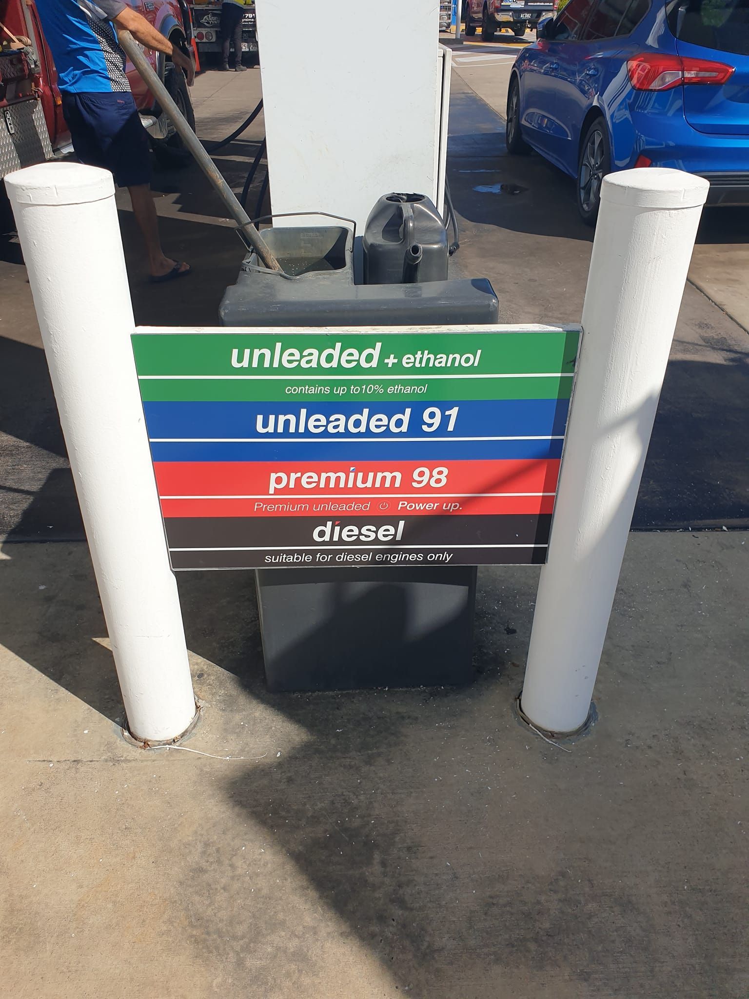 Gasoline price sign: green, blue, red, white, with prices for various fuel types.