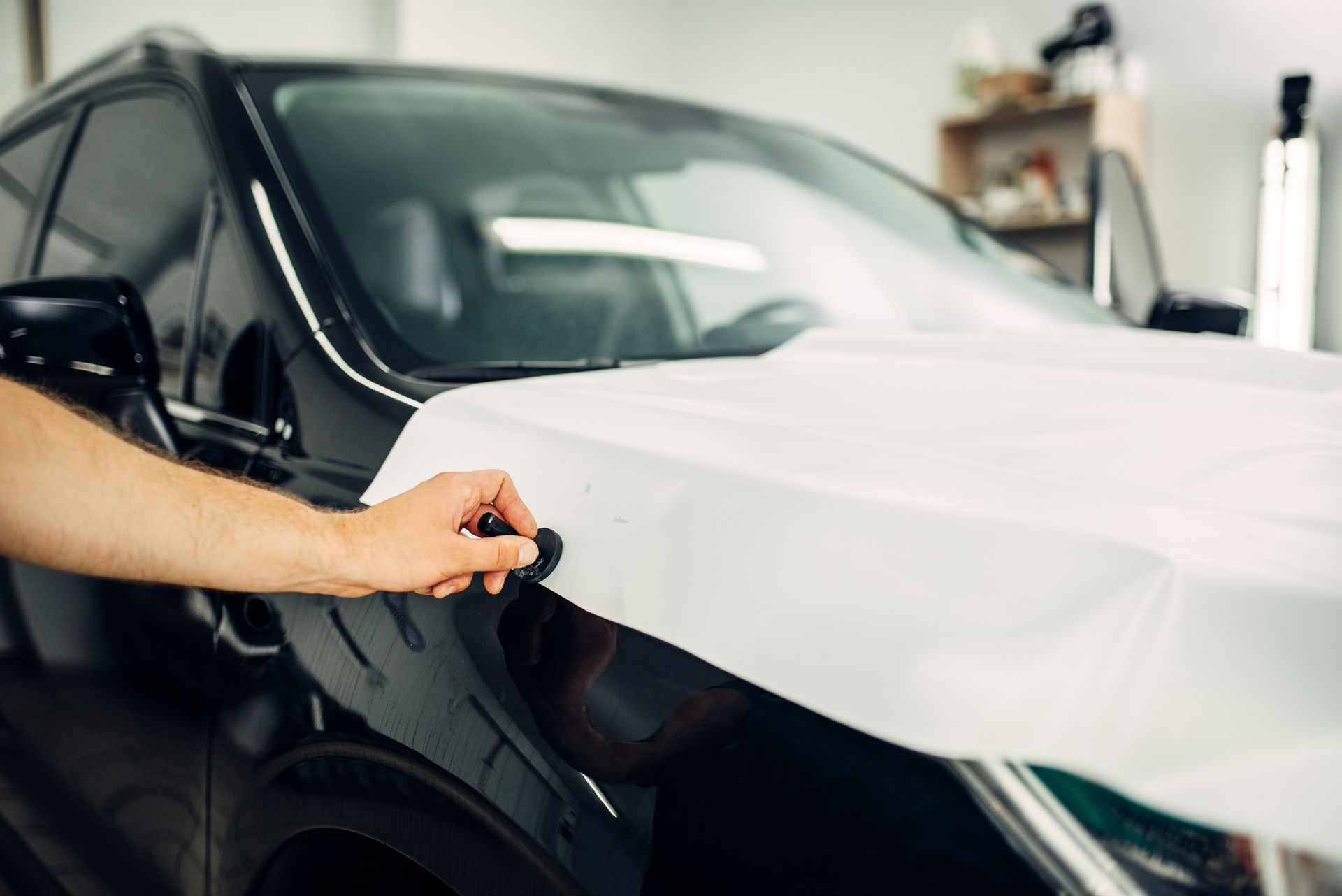 Technician applying a white vinyl car wrap on a black vehicle for a custom finish in Townsville.