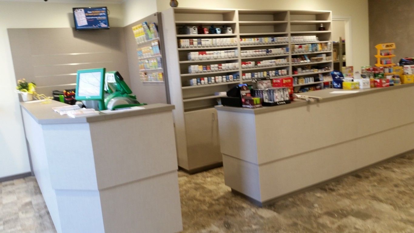 Bancone della farmacia con scaffali di medicinali, registratori di cassa e articoli in esposizione in un luminoso interno del negozio.