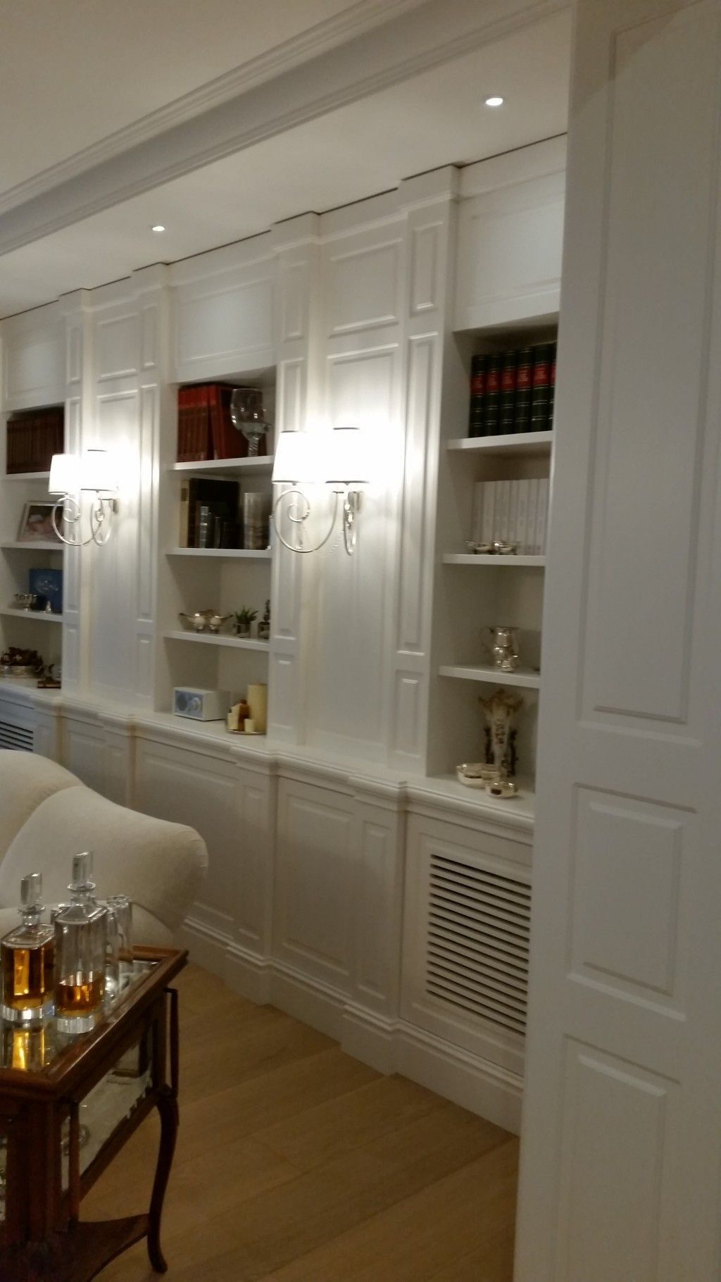 Eleganti scaffali a muro bianchi con oggetti decorativi e libri in un luminoso soggiorno moderno.