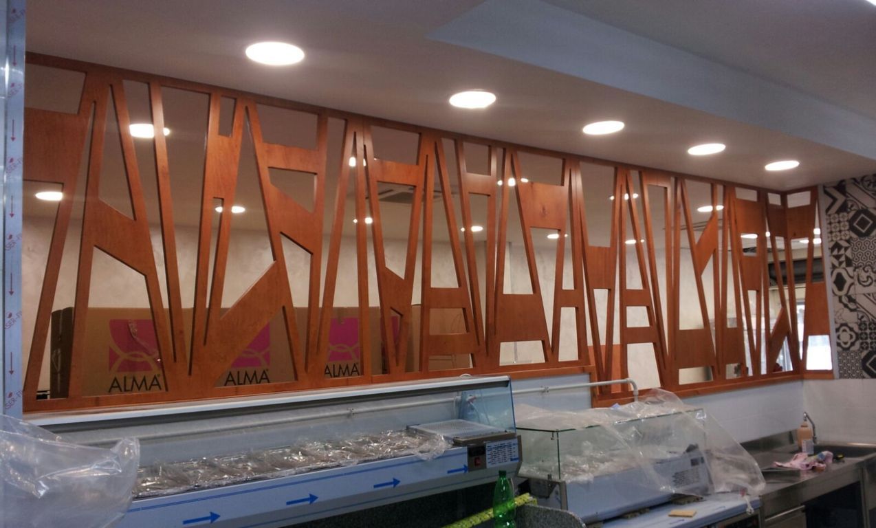 Interno moderno con pannelli a griglia in legno arancione e faretti a incasso a soffitto sopra un bancone.