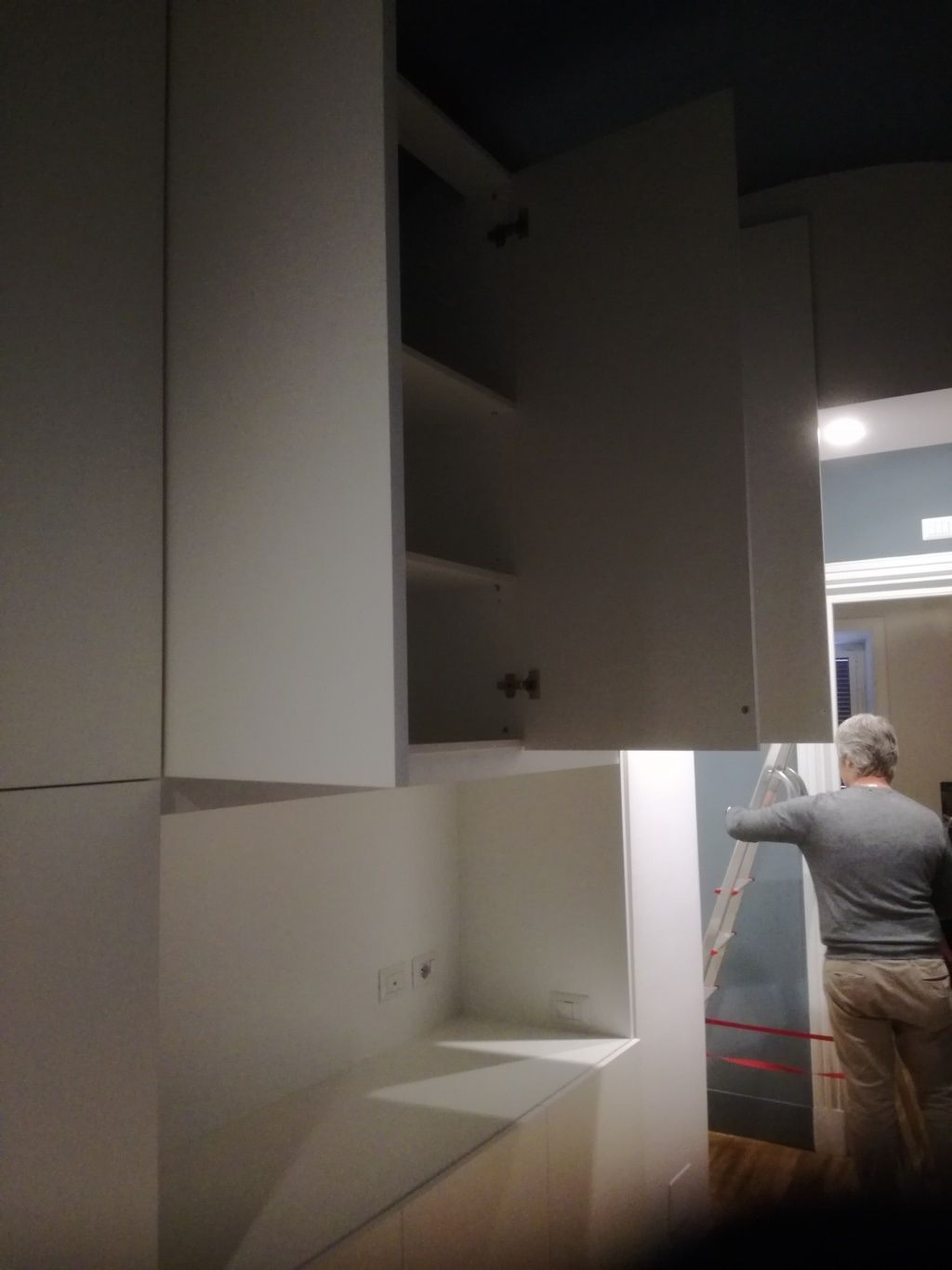 Un armadio aperto in un corridoio, con una persona in piedi nelle vicinanze, vicino a una porta.