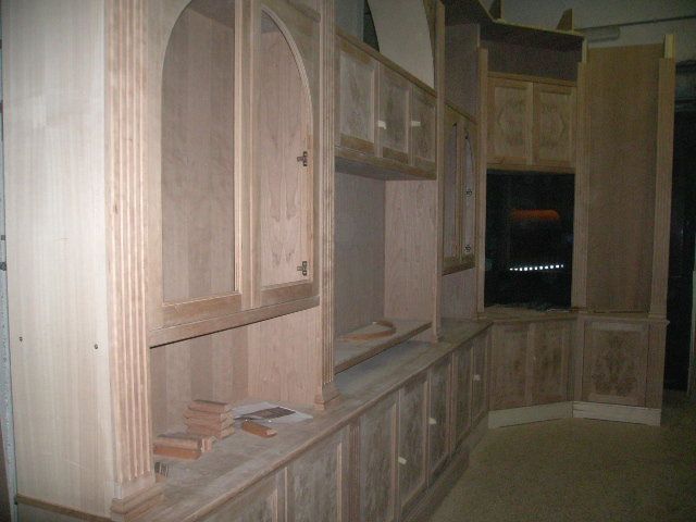 Cucina con pannelli in legno, mobili, piano di lavoro e forno a incasso in una stanza poco illuminata