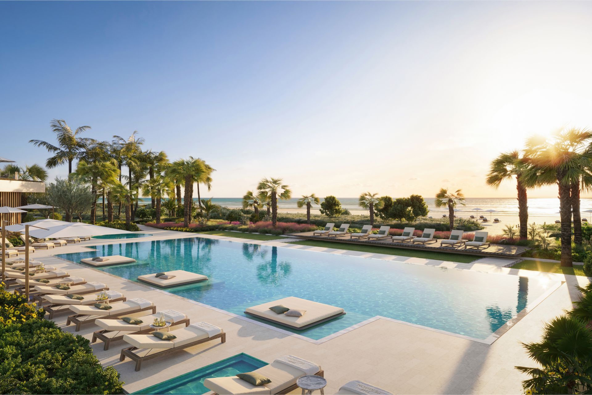 Luxurious resort pool at sunset with palm trees and lounge chairs overlooking the ocean