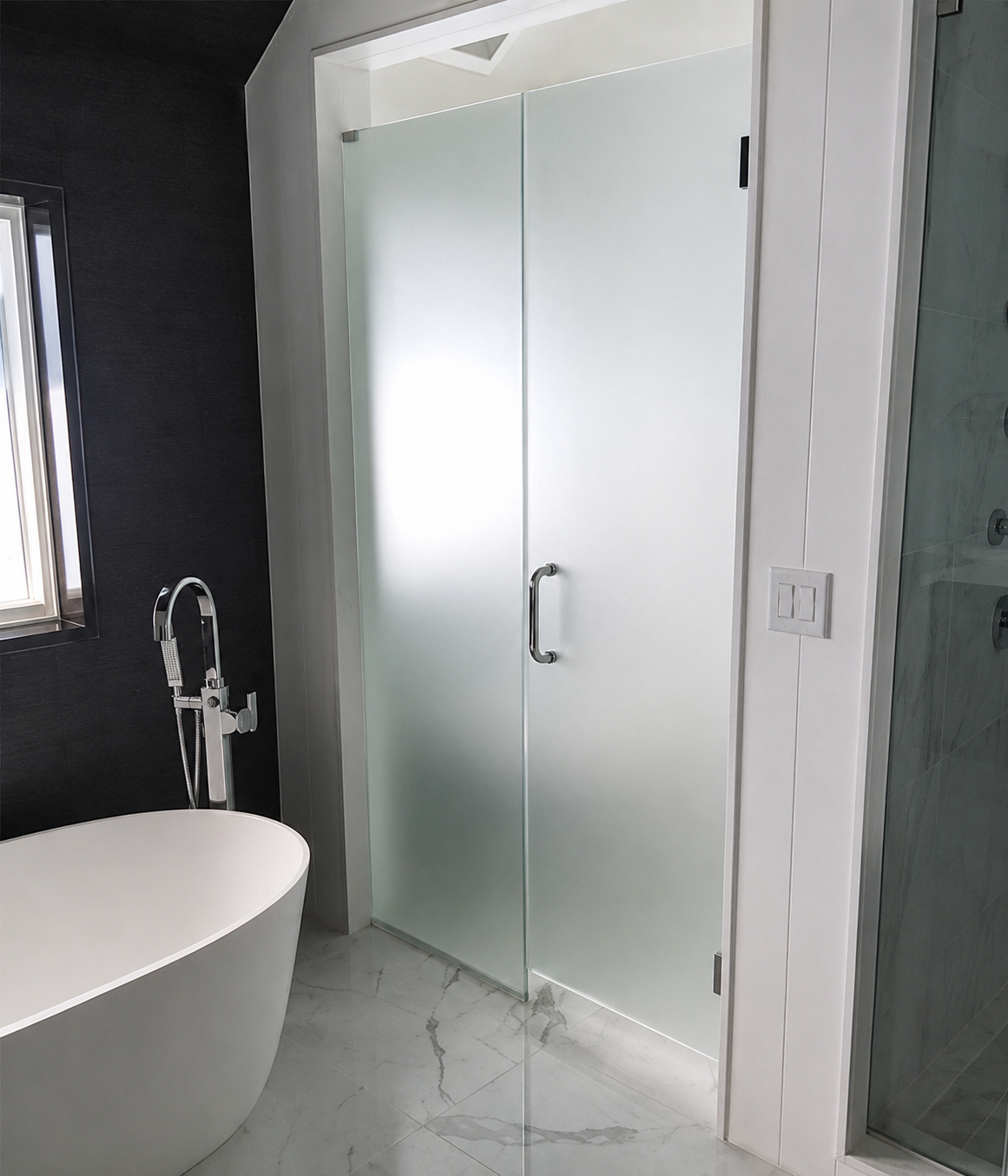 Modern bathroom with frosted glass shower doors, a white tub, and dark walls.