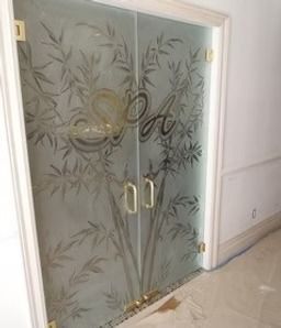 Frosted glass double doors with gold handles and leaf pattern in a hallway