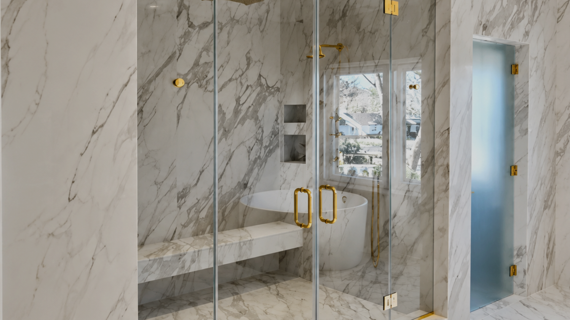 Modern marble shower with glass doors, gold handles, built-in bench, and frosted glass partition