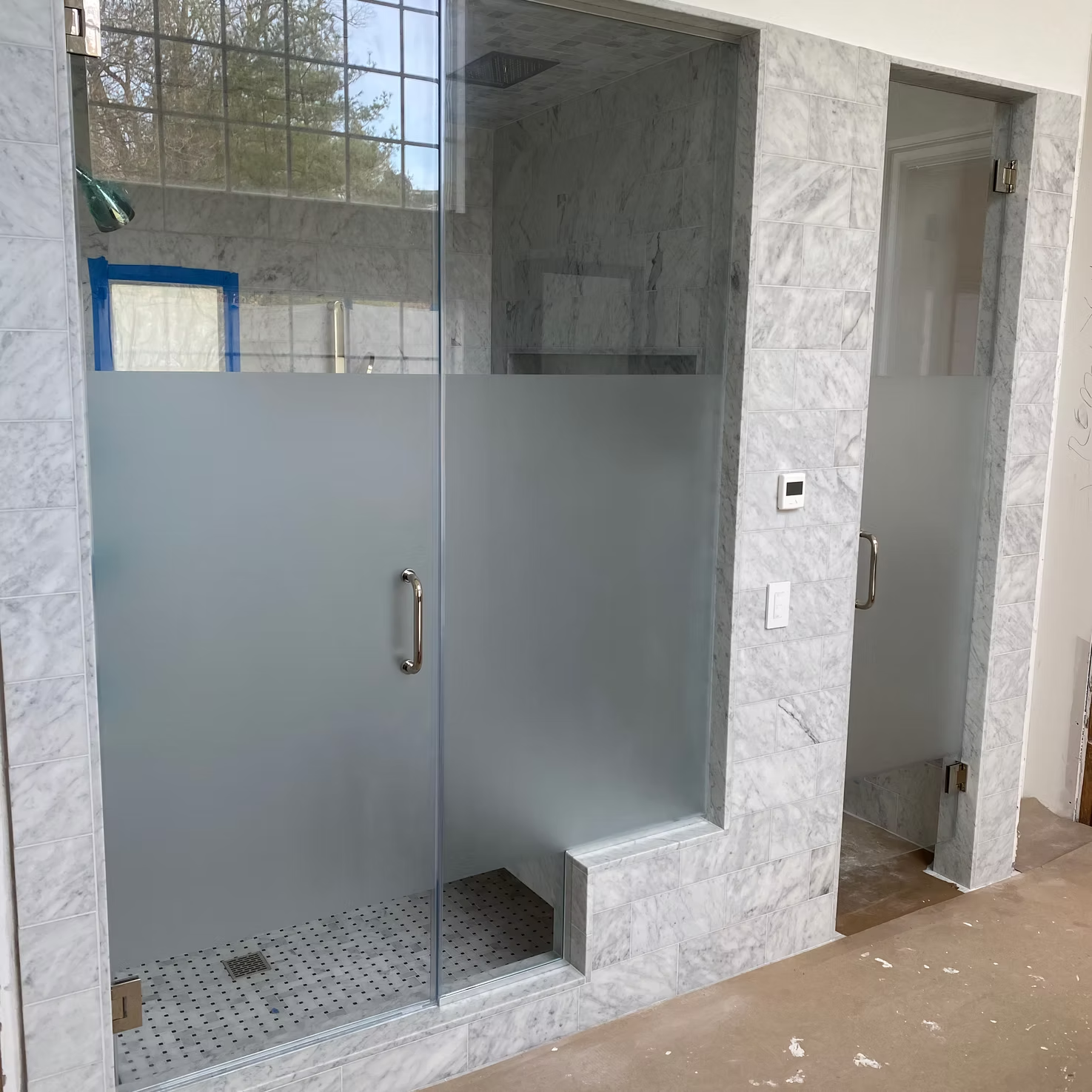 Modern bathroom with frosted glass shower doors and white marble tile walls