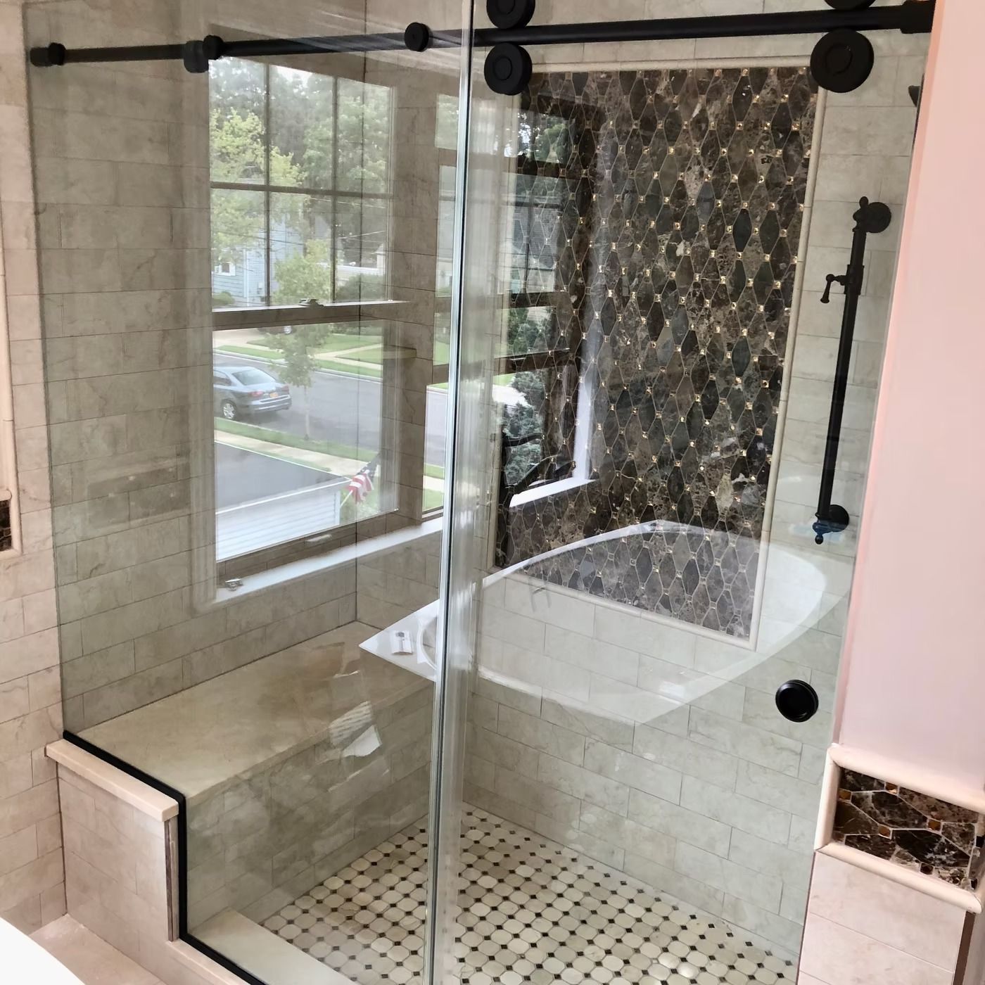 Glass-enclosed tiled shower with bench, window, and corner soaking tub in a bright bathroom