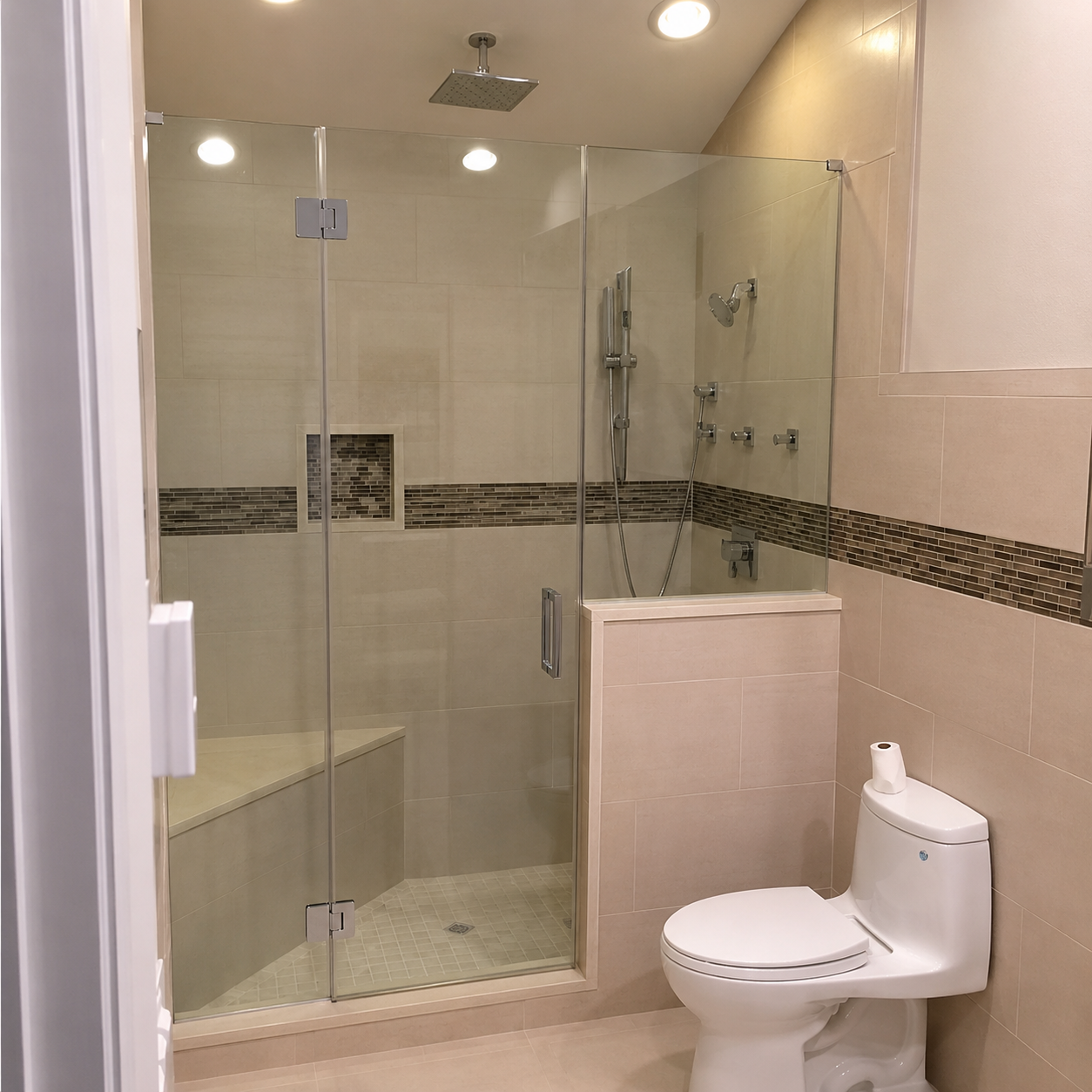 Small tiled bathroom with glass shower, toilet, and tan walls.