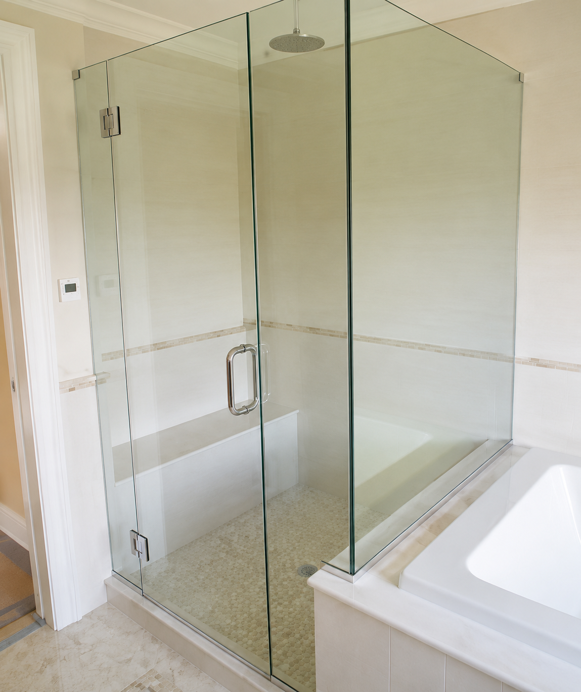Glass shower enclosure beside a white bathtub in a modern bathroom.