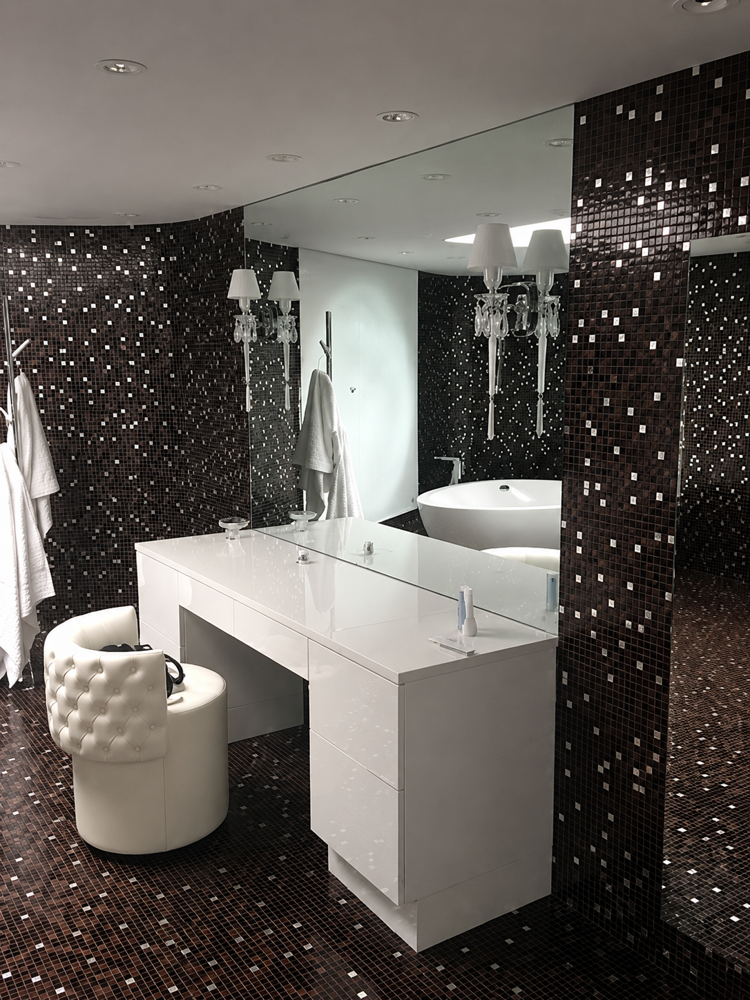 Modern bathroom with white vanity, large mirror, tub, and black mosaic tile walls and floor.